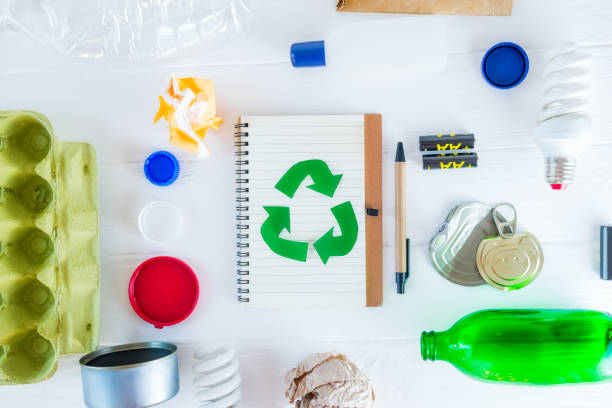 istock Top view recycle paper notebook with Green eco symbol surrounded with non recycling garbage and reusable waste as metal, plastic, old paper, glass products on the white wooden background. Flat lay. 1145481370