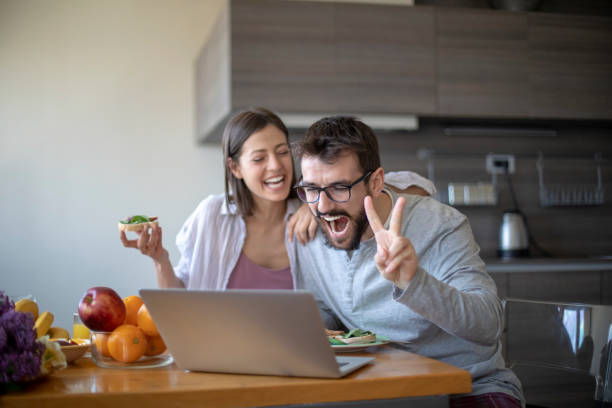 istock Young couple with vegan breakfast in dining room and computer having web call 1145483221