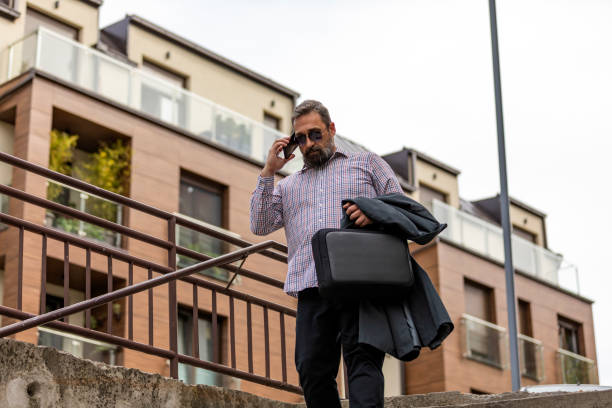 istock Handsome mature creative freelance businessman talking on the mobile phone and smiling while walking outdoor urban area in the street in Staying connected and entrepreneur creative business concept. 1145484698