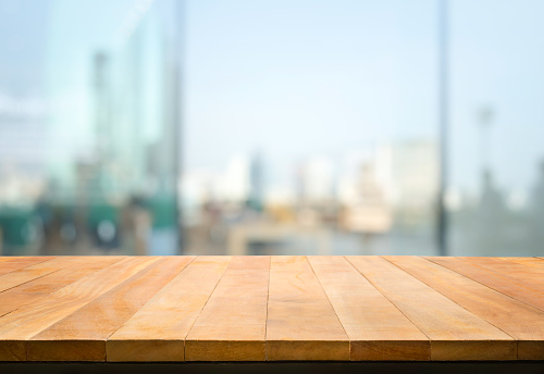 Wood table top on blur window glass,wall background with city view.For montage product display or design key visual layout