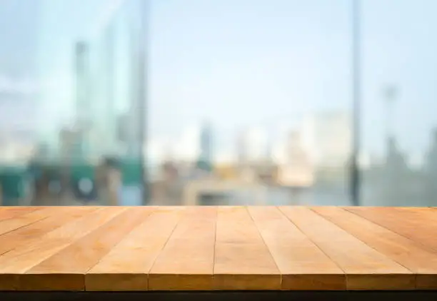 Wood table top on blur window glass,wall background with city view.For montage product display or design key visual layout