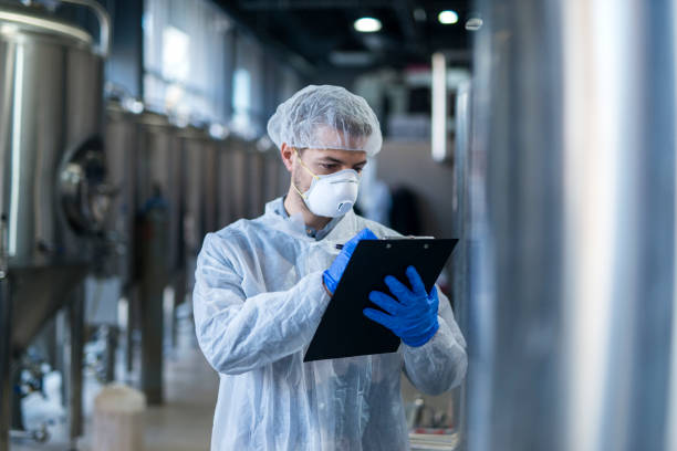 istock Technologist specialist keeping track of production process and writing notes in his logbook. Responsible young man at his workplace. 1145493190
