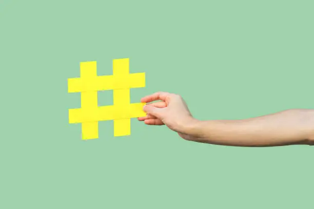 Photo of Social media concept, closeup portrait of hand holding large big yellow hash tag sign.