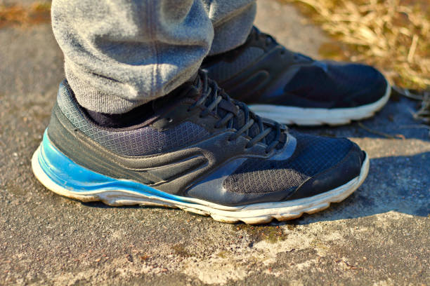 istock Legs in gray sweatpants and black running shoes sneakers with white and blue soles on the asphalt concept for healthy and active sport lifestyles 1145493473