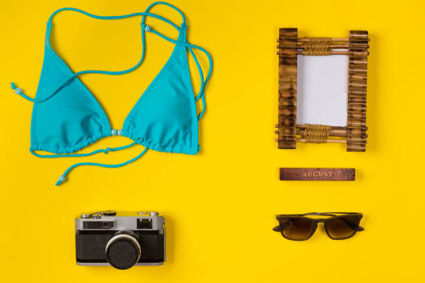 istock swimsuit, frame, camera, sunglasses on a yellow background, top view 1145495171