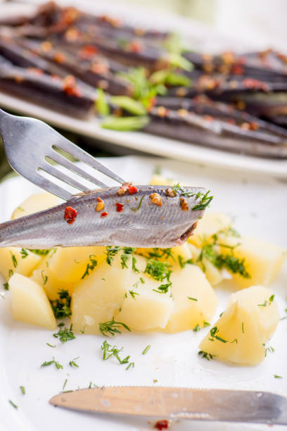 Small fish of sprat with spices on a fork