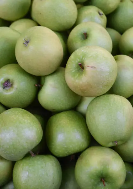 Farmers market with a bushel fo green apples at a Farmers Market.