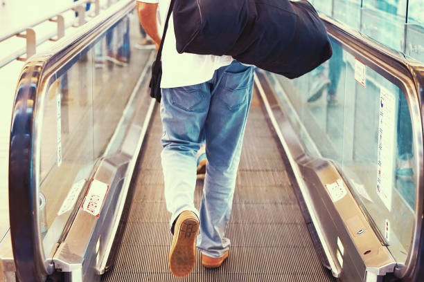 un uomo con i bagagli su una scala mobile orizzontale - moving walkway escalator airport walking foto e immagini stock