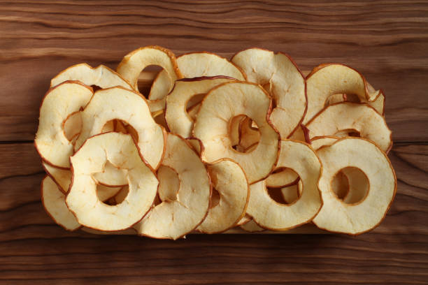 istock Apple chips lying on a bamboo plate on a wooden table. Closeup. Macro 1145506661