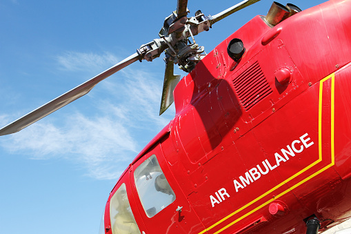Red helicopter of air ambulance isolated on blue sky background. Detail of the helicopter blades. Cornwall, UK