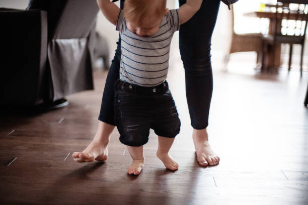 istock Parents Watching and Helping Baby Son Take First Steps At Home 1145513330
