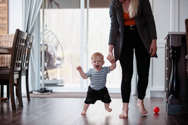 istock Parents Watching and Helping Baby Son Take First Steps At Home 1145513439