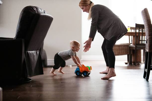 istock Parents Watching and Helping Baby Son Take First Steps At Home 1145514408