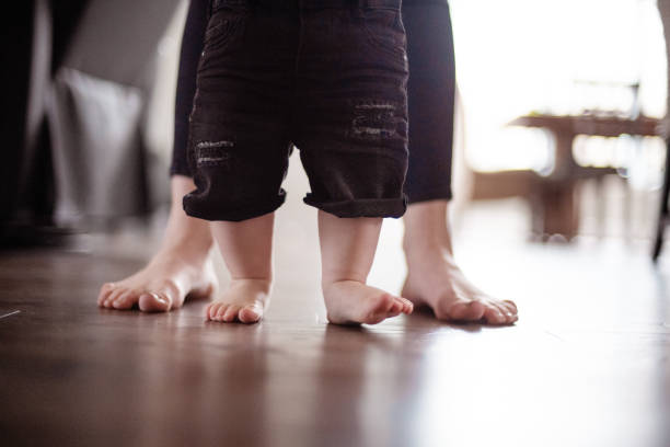 istock Parents Watching and Helping Baby Son Take First Steps At Home 1145514418