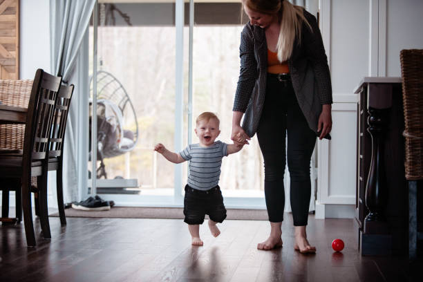 istock Parents Watching and Helping Baby Son Take First Steps At Home 1145515482