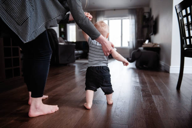 istock Parents Watching and Helping Baby Son Take First Steps At Home 1145515757