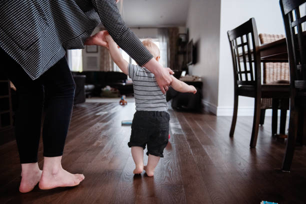 istock Parents Watching and Helping Baby Son Take First Steps At Home 1145515885
