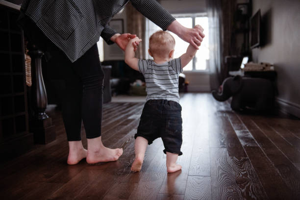 istock Parents Watching and Helping Baby Son Take First Steps At Home 1145516927