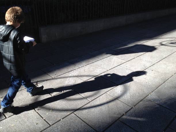 Little boy walking down the street \nlooking for an address on a map. Side view.