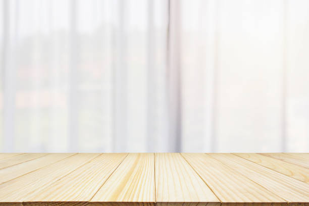 istock Empty wood table top with window curtain abstract blur background for product display 1145534094