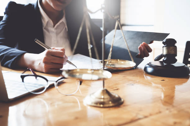 geschäftsfrau und anwälte diskutieren vertragsunterlagen mit messingskala auf holztisch im büro. rechts-, rechts-, beratungs-, justiz-und immobilienkonzepts. - dismiss stock-fotos und bilder