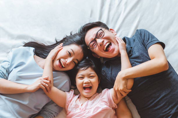 Happy Asian family laying on bed in bedroom with happy and smile, top view stock photo