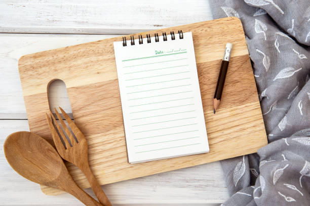 istock book notepad paper on a chopping cutting board and tablecloth on white table , recipes food  for healthy habits shot note background concept 1145565481