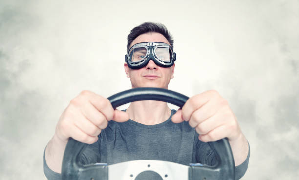 istock Confident man in stylish goggles with steering wheel, smoke around. Front view. Car driver concept 1145571856