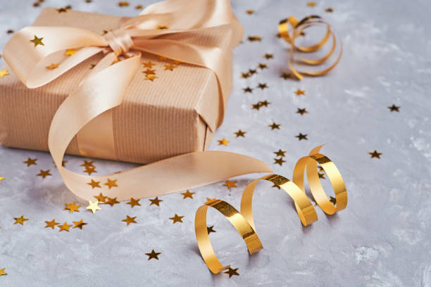 istock Gift box with golden bow and confetti, close up 1145573827