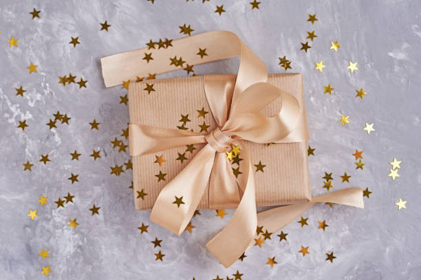 istock Gift box with golden bow and confetti, close up 1145573828