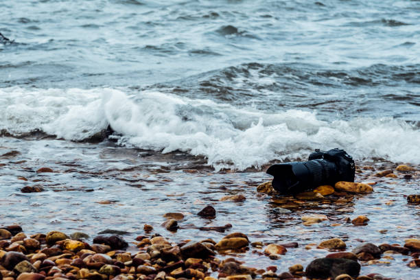 istock DSLR camera on stone beach wet from water sea wave 1145581986