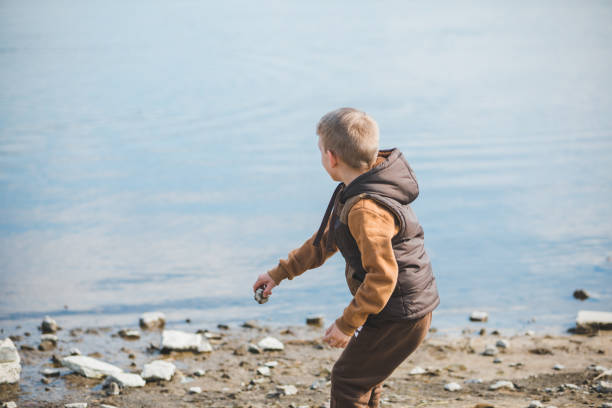 mały chłopiec na plaży trowing skały do wody - throwing stone little boys child zdjęcia i obrazy z banku zdjęć