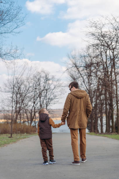 istock father with son walking by park holding hands 1145583380