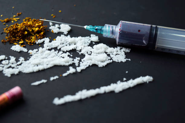 istock Cocaine and Indonesia rupiah ready for uses on dark table. Selective focus on syringe 1145584452