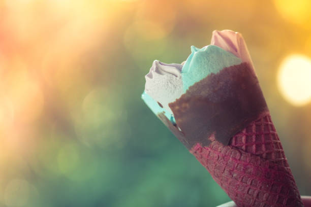 istock Ice cream pink wafer cone against on nature blur background 1145588285