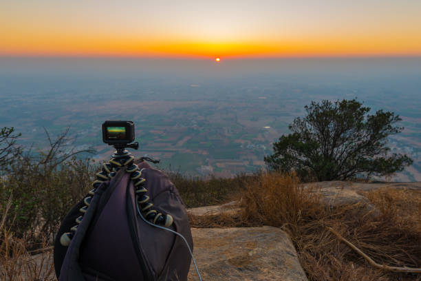 Capturing time lapse of the sunrise using an action camera mounted on a tripod on top of a camera bag. Morning Sunrise from Hill Top view point after hiking for 2 hours at mid night near Bangalore. People go hiking to this place overnight just to see the sunrise and is the nearest weekend destination.