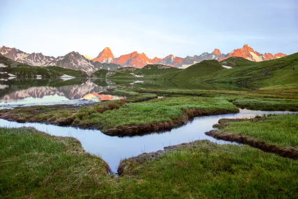 Wetland with winding brooks at Lacs de Fenetre with reflection at sunrise and Grand Jorasses; Val Ferret; Mont Blanc; Col de Grand Saint Bernard at the mountain background, Switzerland