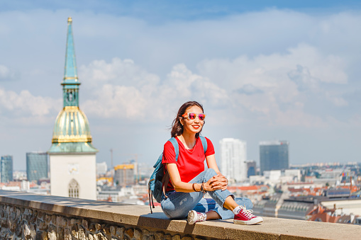 Traveler woman tourist with backpack and sunglasses resting at observation point to Bratislava city