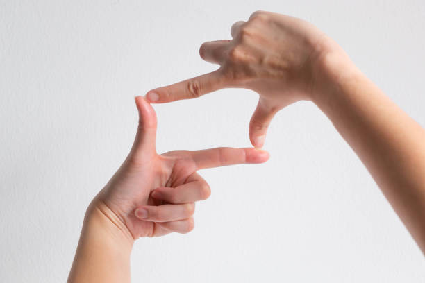 A person using thumb and forefinger of two hand to make a shape of camera frame on white background; concept of make a focus or have an aim.