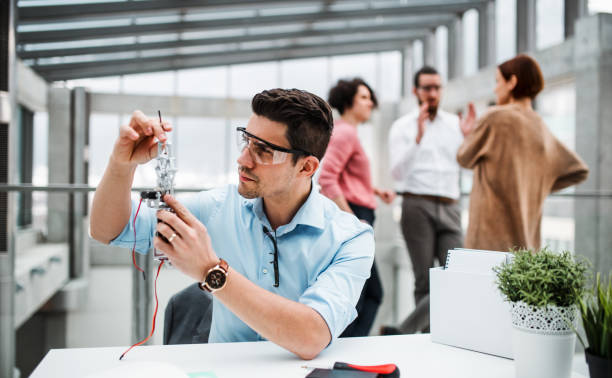 istock A young businessman or scientist with robotic hand standing in office, working. 1145610249