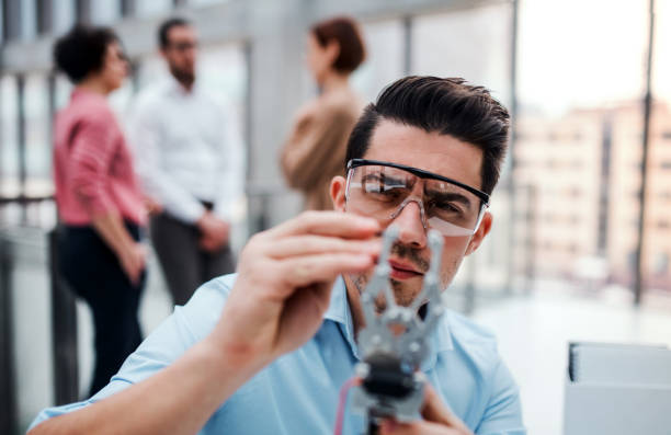istock A young businessman or scientist with robotic hand standing in office, working. 1145610257