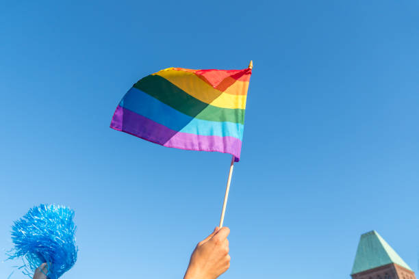 istock LOW ANGLE VIEW OF HAND HOLDING rainbow flag AGAINST SKY 1145618509