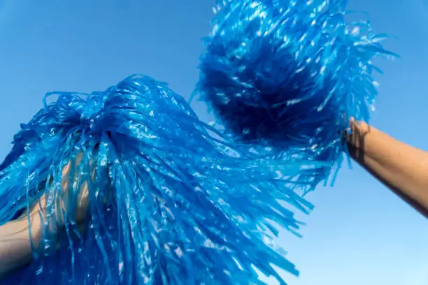 CLOSE-UP OF HANDS HOLDING BLUE POMPOM IN SUMMER