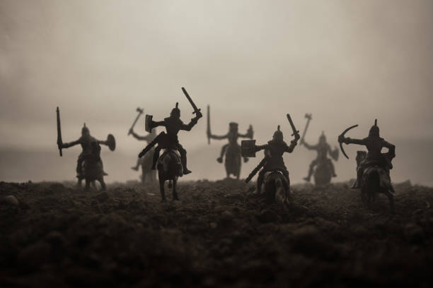 istock Medieval battle scene with cavalry and infantry. Silhouettes of figures as separate objects, fight between warriors on sunset foggy background. Selective focus 1145618702