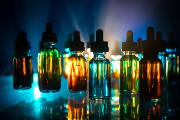 istock Vape concept. Smoke clouds and vape liquid bottles on dark background. Light effects. Useful as background or electronic cigarette advertisement. 1145619839