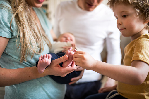 Sección media de padres con un bebé recién nacido y un hijo pequeño en casa. photo