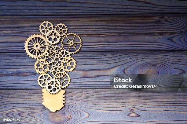 Wooden Gears In The Form Of A Light Bulb On A Wooden Background Stock Photo - Download Image Now