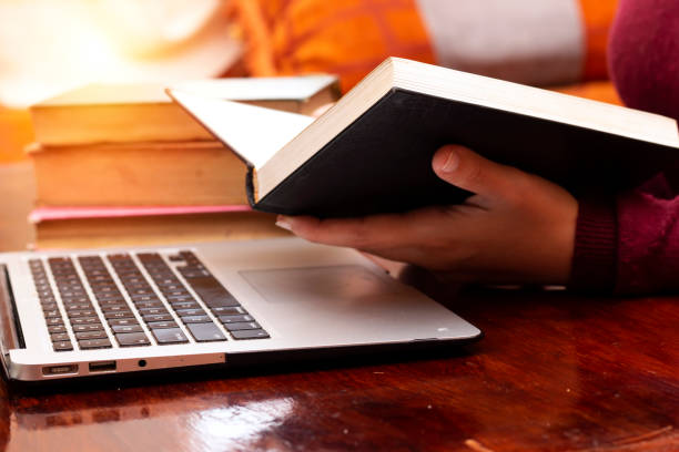 istock closeup women reads a book and using a laptop 1145627477