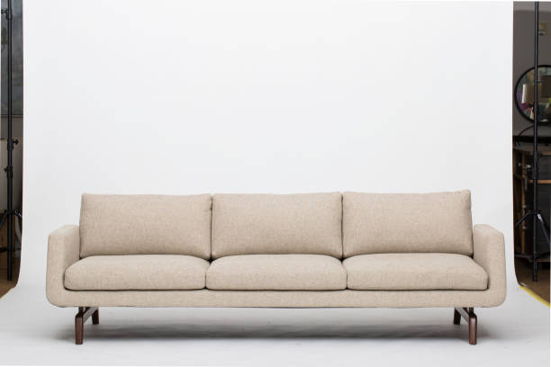 istock Comfortable Cream colour three seater wooden sofa with white background 1145628543