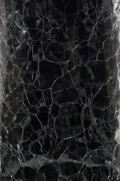 Photo of Structure of cracked glass on black background